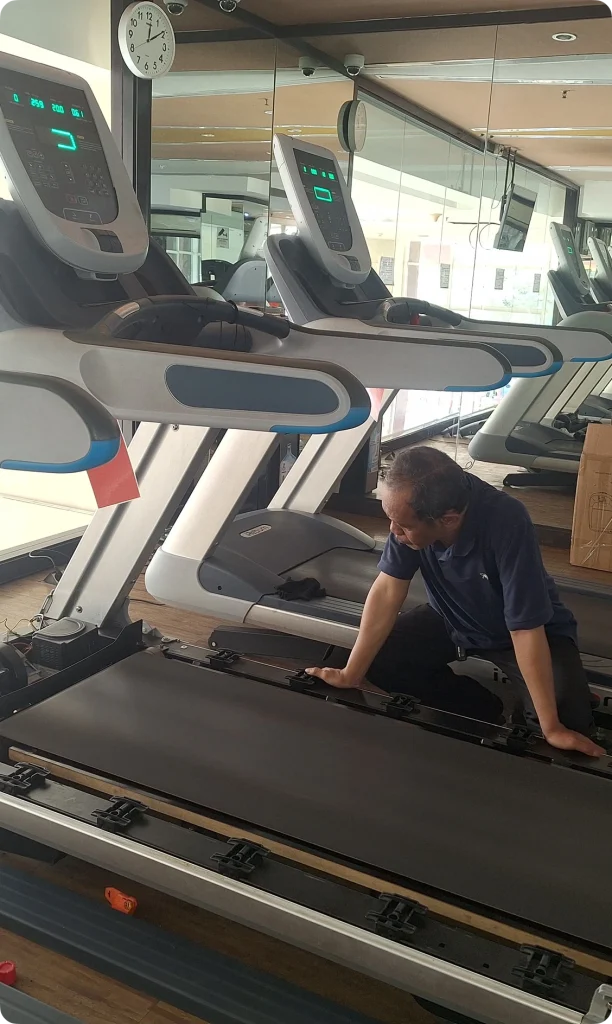 Proses penggantian atau pengecekan karpet running belt treadmill oleh teknisi berpengalaman