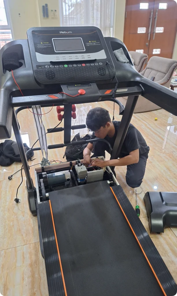 Layanan service treadmill di rumah pelanggan, teknisi sedang membongkar komponen mesin untuk perbaikan